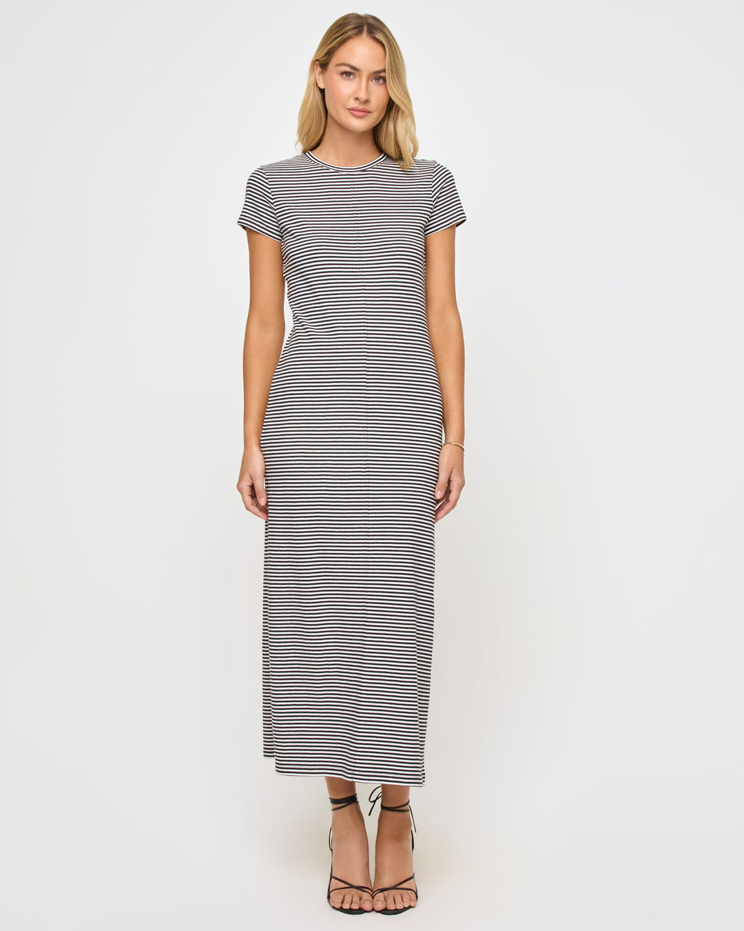 Front view of a model wearing the LSPACE Sloane Dress in black-cream, a fitted maxi dress with black and cream horizontal stripes, a crew neckline, and short cap sleeves.