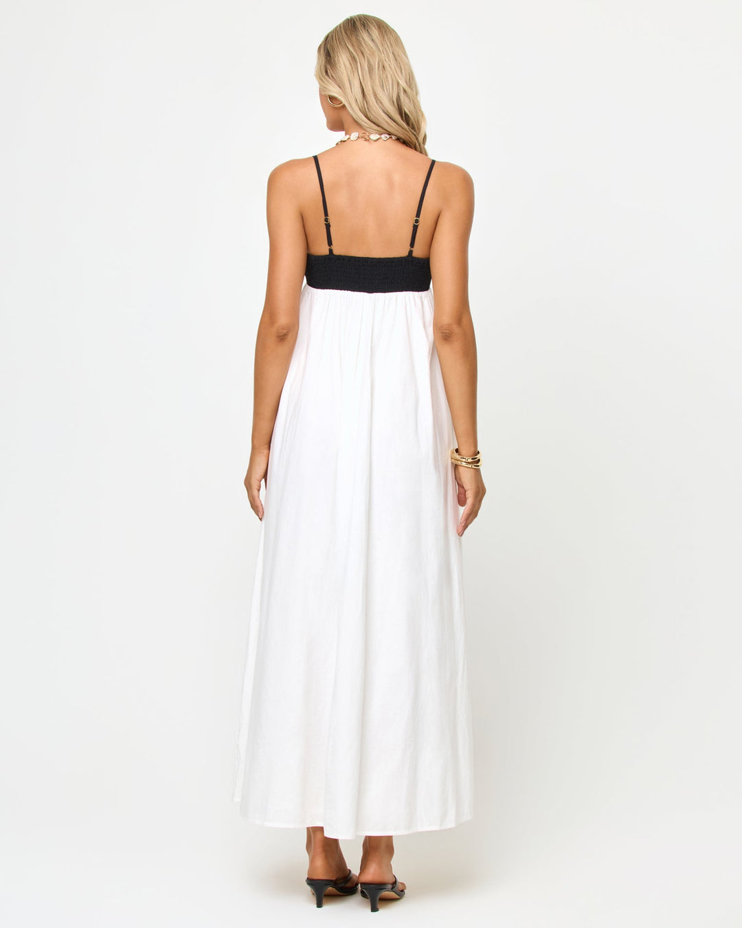Back view of a model wearing the LSPACE Raveena Dress in black-cream, showing the adjustable spaghetti straps against the black bodice and the full flowing cream maxi skirt.