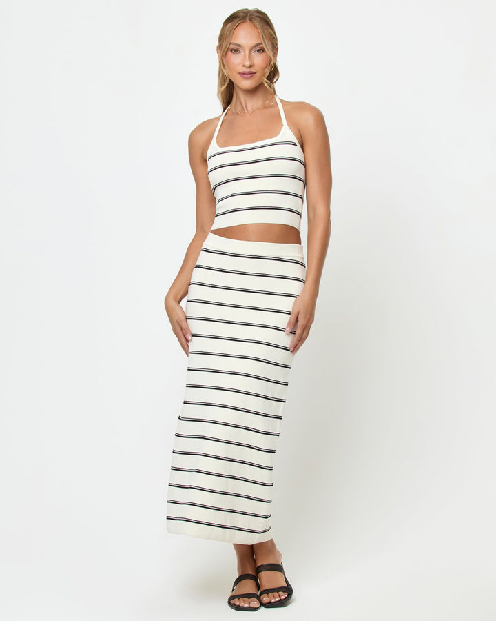 Front view of a model wearing the LSPACE Ravello Skirt in mykonos stripe, a ribbed fitted midi skirt with cream and black horizontal stripes and a cream waistband, styled with the matching Positano Top.