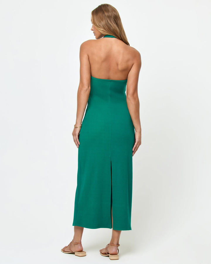 Back view of a model wearing the LSPACE La Femme Dress in Isle on a white background, showing the open back with halter tie and center back slit of the emerald green ribbed knit maxi dress.