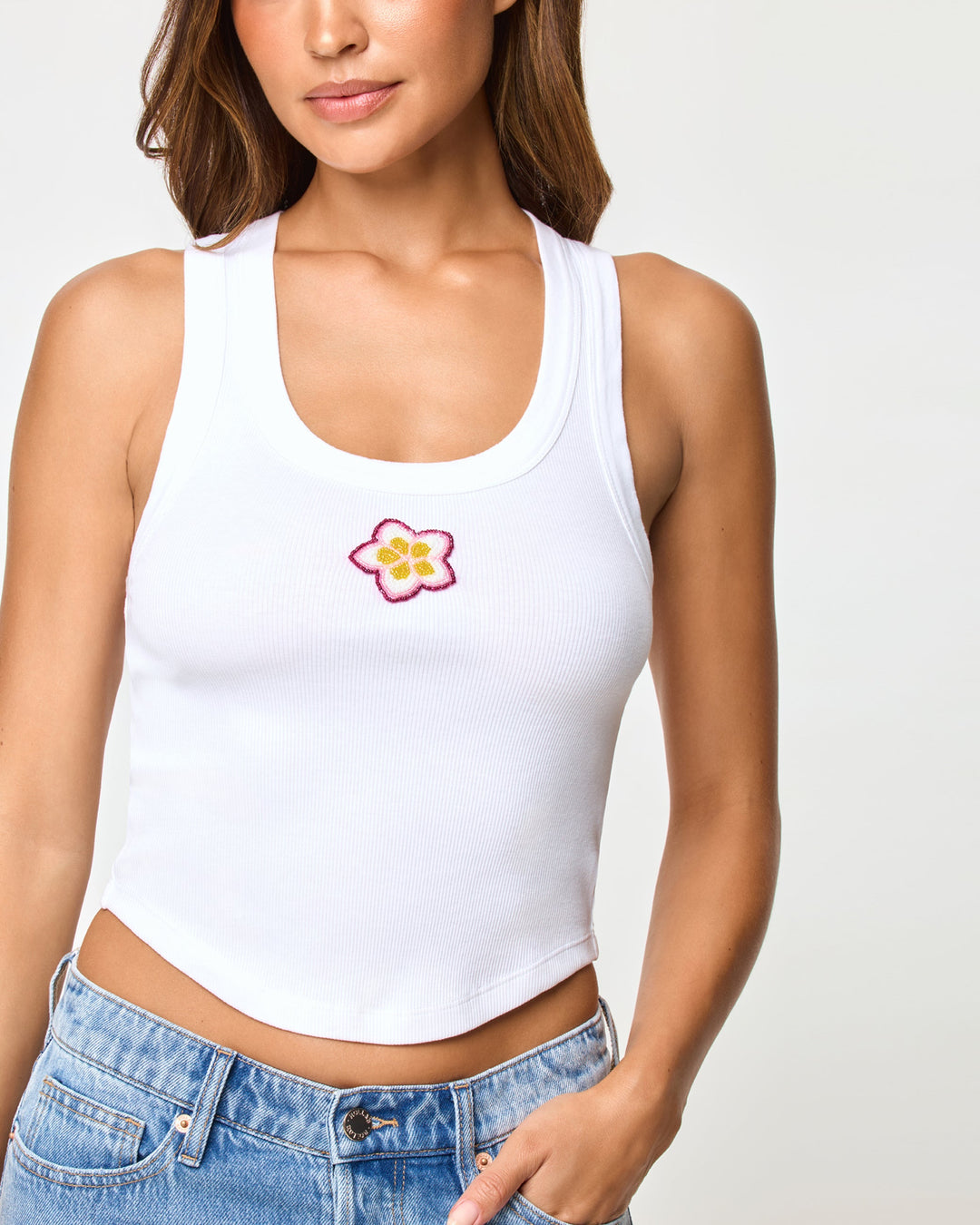 LSPACE Ash tank in Plumeria, close-up detail view of embroidered plumeria graphic on model.