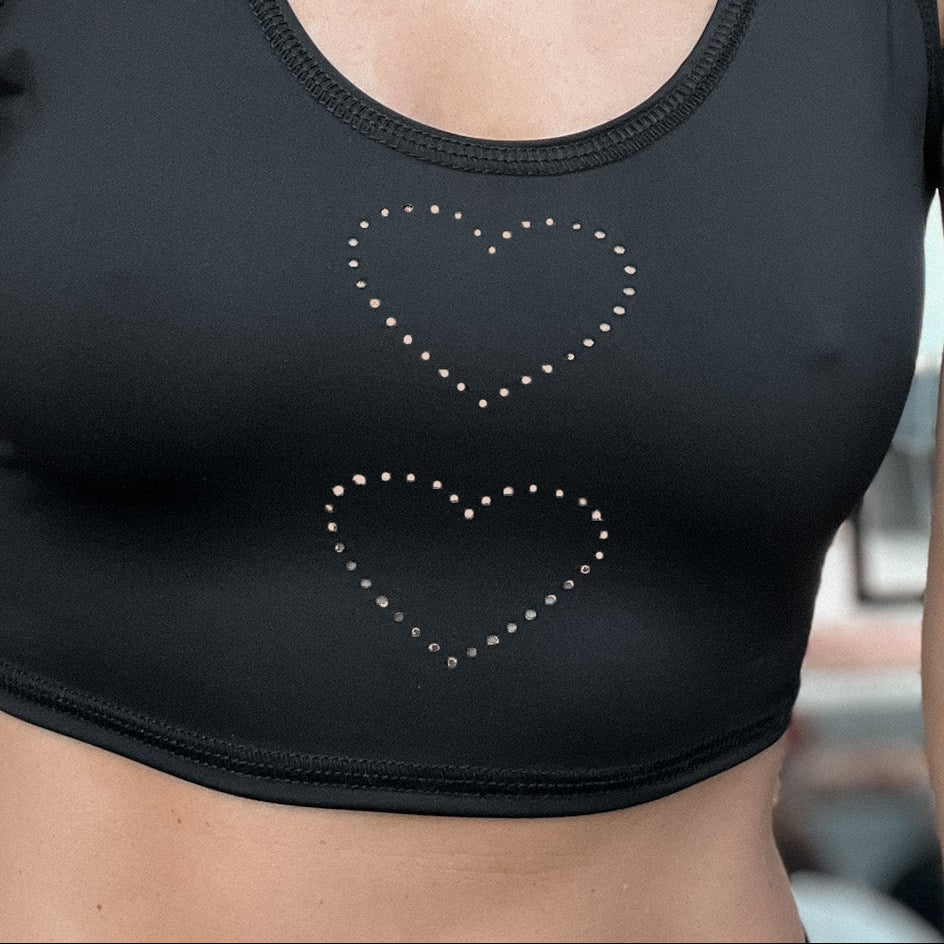Black sports bra with heart designs worn by a person.