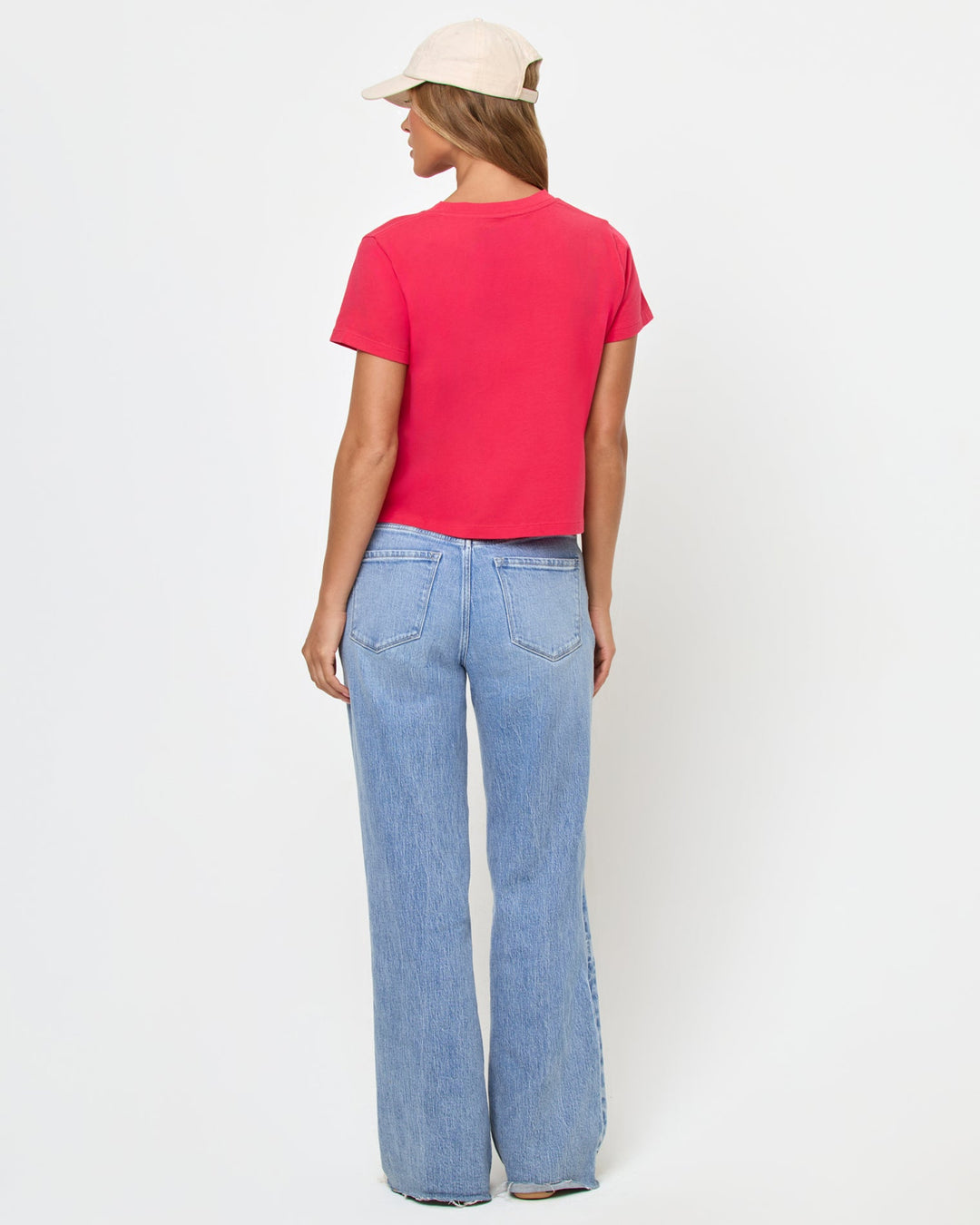 Back view of a model wearing the LSPACE All Day Top in pout, a cropped crew-neck tee with short sleeves, paired with light wash wide-leg jeans.