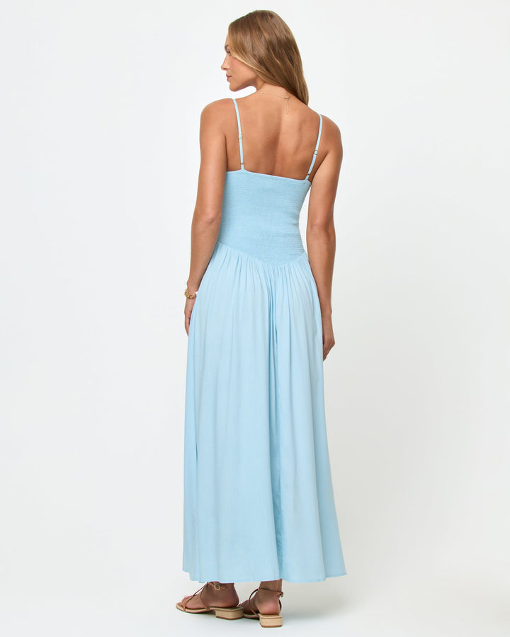 Back view of a model wearing the LSPACE Misha Midi in Tourmaline, showing the open back with thin spaghetti straps, smocked back bodice, and full gathered powder blue midi skirt.
