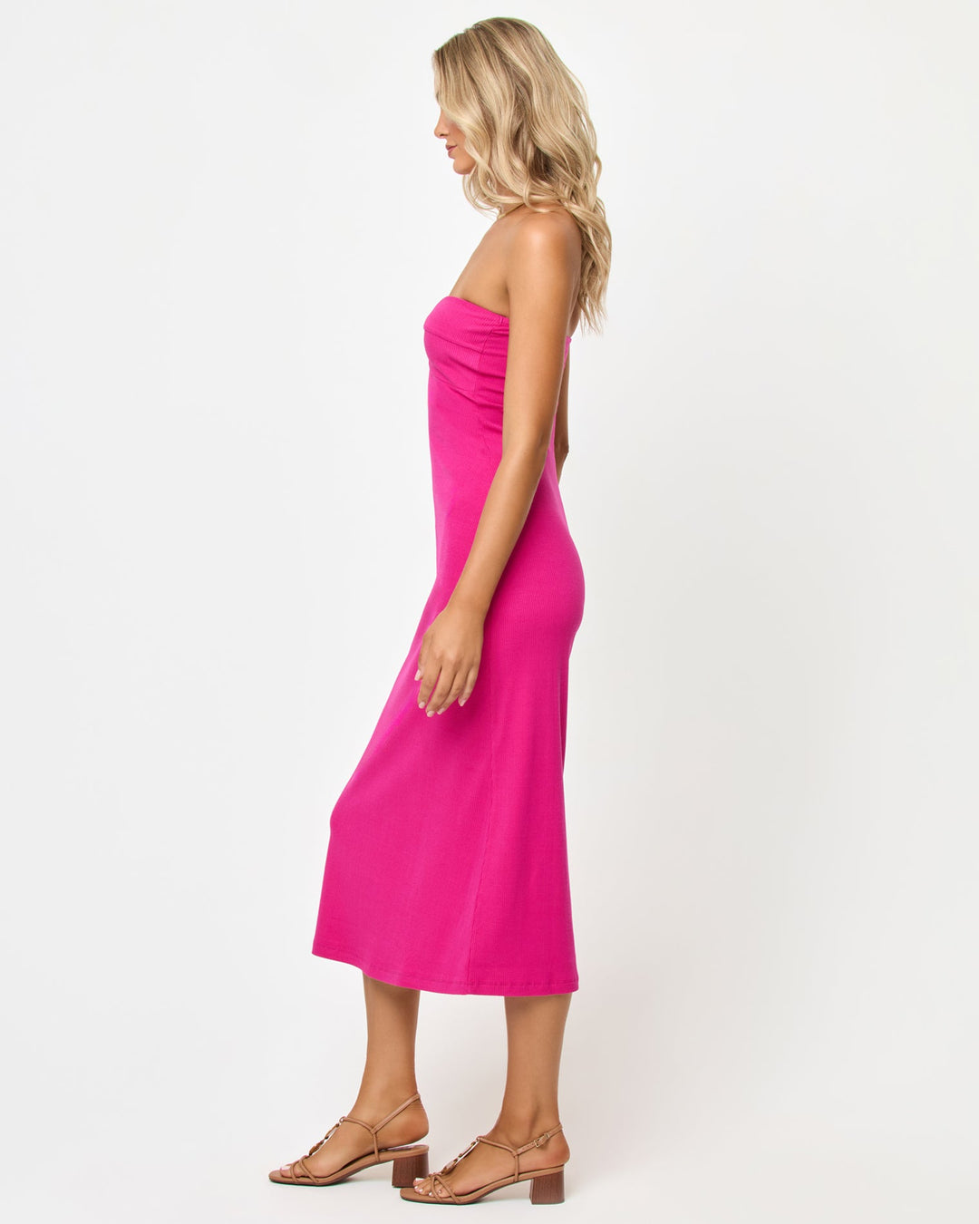 Side view of a model wearing the LSPACE Lisette Dress in bougainvillea, showing the form-fitting ribbed midi silhouette and strapless neckline.