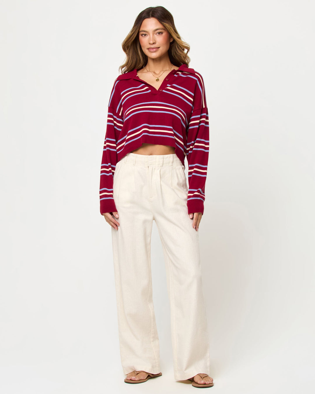 LSPACE Dalton sweater in berry wine stripe, styled with pants, front view on model.