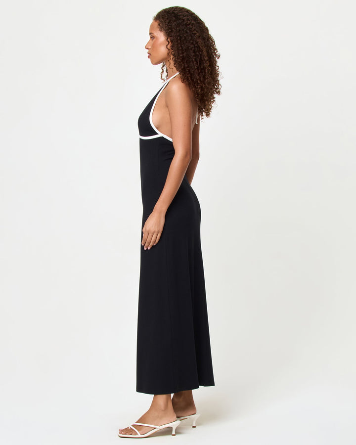 Side view of a model wearing the LSPACE Shea Maxi Dress in black-cream, showing the fitted silhouette and full length of the dress with cream contrast trim detail.