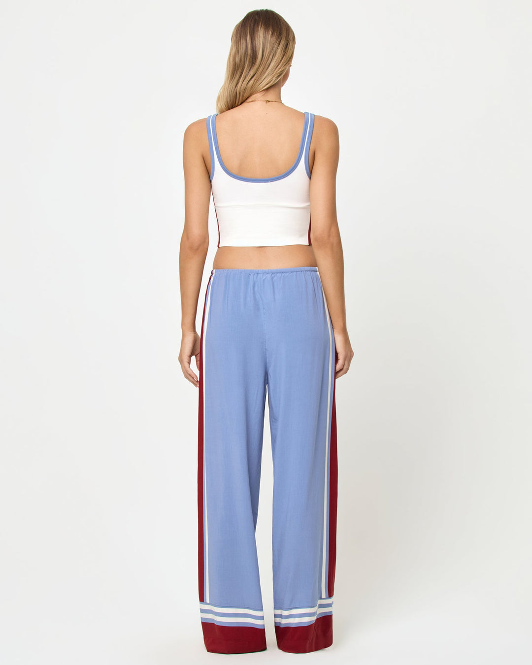 Back full-length studio view of the Reset Tank in Cream-Chambray-Fig, a cream ribbed scoop-neck crop cami with chambray blue strap trim and burgundy color-block side panels, styled with chambray blue wide-leg stripe pants with burgundy side stripes and stripe trim at the ankle hem.