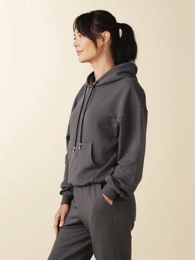 model wears cozy sustainable hoodie with pocket in grey