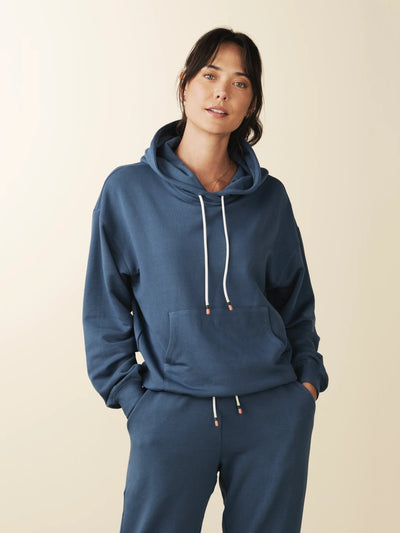 model wears cozy sustainable hoodie with pocket in blue