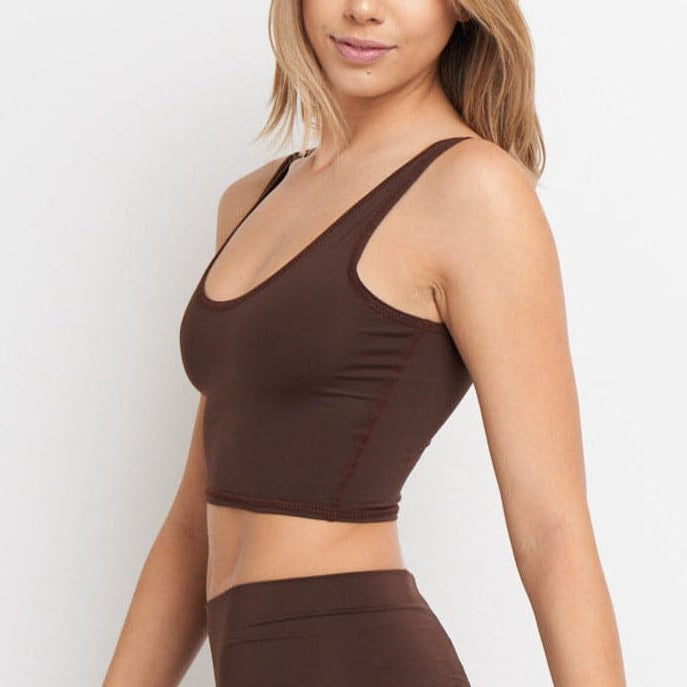 Woman wearing a brown sports bra and leggings on a white background